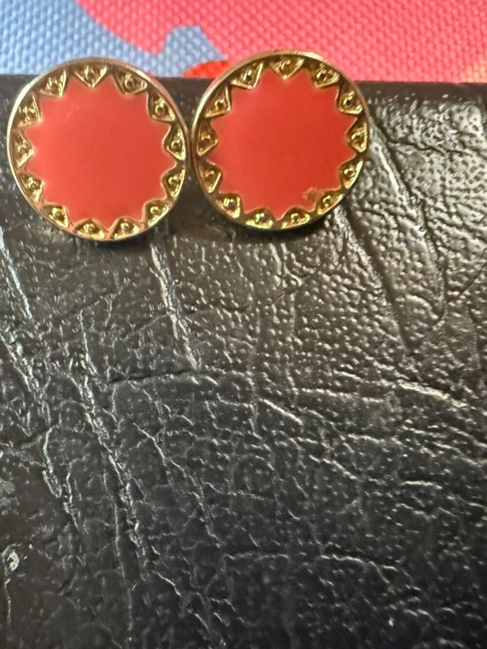 Bright coral oran round stud earrings with decorative gold-tone sunburst border.